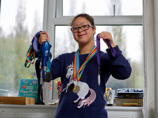 Portrait of girl with Down syndrome showing medals