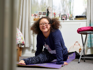 Smiling girl with Down syndrome doing splits - obrazy, fototapety, plakaty