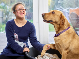 Smiling girl with Down Syndrome sitting with her dog