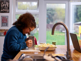 Girl with Down Syndrome using grater in kitchen