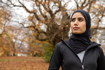 Portrait of woman in black sports clothing and hijab in park