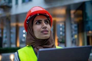 UK, London, Female engineer in hijab and hardhat using digital tablet - obrazy, fototapety, plakaty