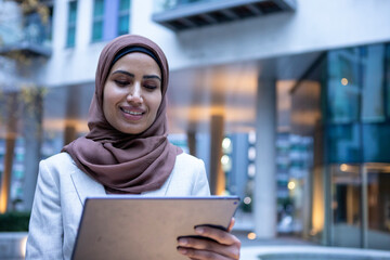 UK, London, Smiling businesswoman in hijab using digital tablet in city - obrazy, fototapety, plakaty