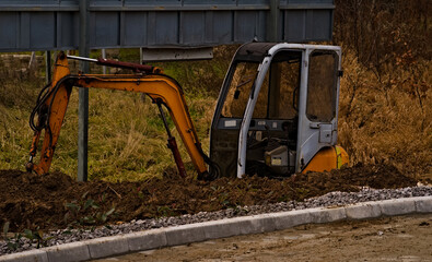 Mała koparka gąsienicowa kopiąca rów . Small crawler excavator digging a trench.  © Grzegorz