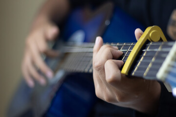 young man playing blue guitar with bonnet on the strings