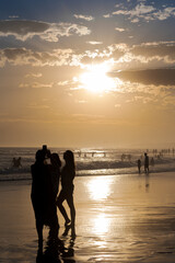 Silhouettes of people taking photos on the beach at sunset