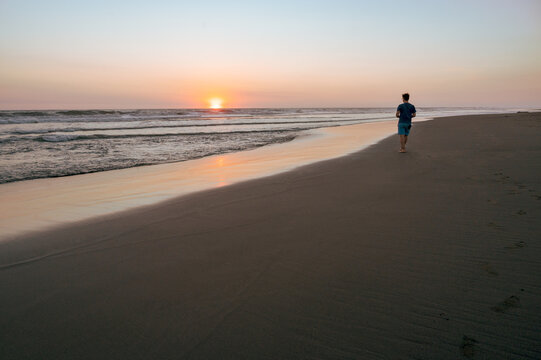 person walking on the beach at sunset with footsteps in sand - Montericco, Guatemala, Pacific Ocean