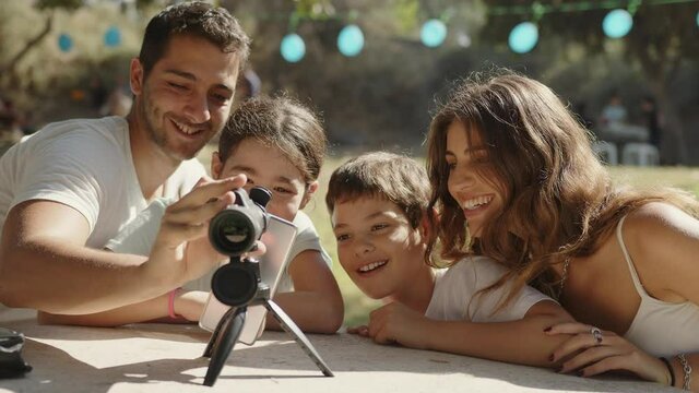 A happy family is excited at the park enjoying their monocular telescope. Medium shot