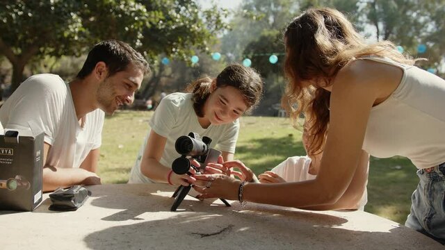 Mom hand over a monocular telescope as a present to her children at the park.
