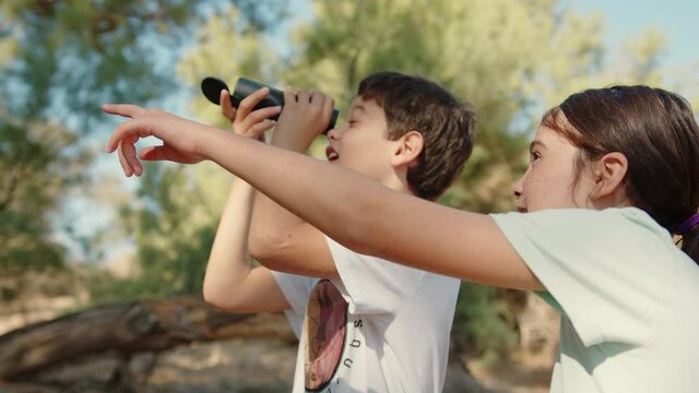 A female kid passed over a monocular telescope to her brother and pointing up