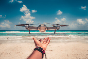 Drone despegando de la mano de un hombre en un día soleado en la playa