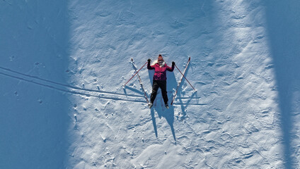 Luftaufnahme mit einer Drohne von einer Frau mit Langlaufski im Schnee. Wintersport für Senioren