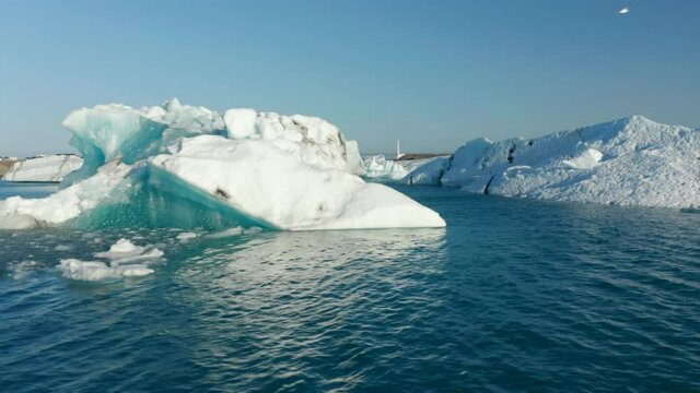 Fly between ice block floating on lake in Nordic nature. Landscape scenery with icebergs and blue sky. Iceland