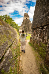 person walking between mayan tempels in ancient mayan city of Tikal - Tikal, Guatemala