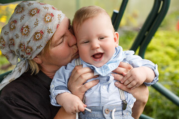 Grandmother kisses a child in the summer in a country house