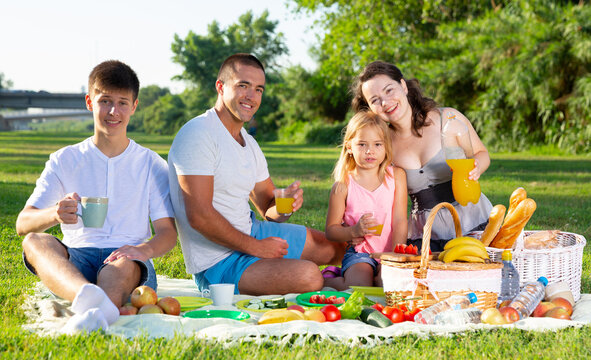 Happy young parents with two teenagers having a picnic on the countryside. High quality photo