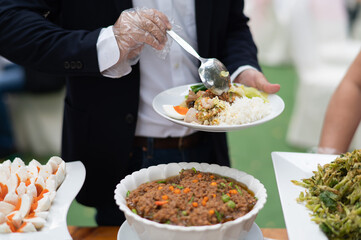 a person wearing gloves scooping food, catering, dinner time, prevent Coronavirus disease (covid 19)