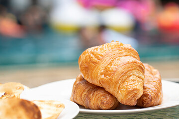 A serving of freshly baked croissants on a white plate. Blurred background