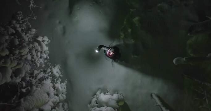 Aerial view above a woman with lantern, lost in winter forests of Lapland - screwdriver, drone shot