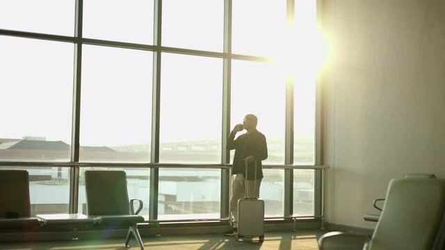 Smart Asian man using mobile phone to play social media with beautiful sunlight. Business man using cell phone for business communication in airport.  Smartphone concept.