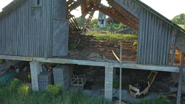 Koeru.Estonia-July 5.2021: Drone shot of an old forgotten soviet farm building. Slowly decaying structure becoming one with nature. Camera slowly moving backwards and upwards.