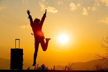 young female tourist carrying luggage at sunset