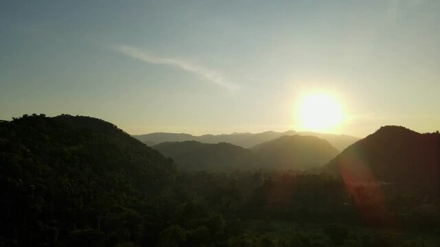 Aerial footage of Khao Yai National Park from a distance sliding to the left during a progressing sunset, Thailand.