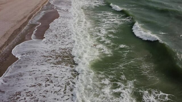 Stormy wavy sea coast beach with green water top view