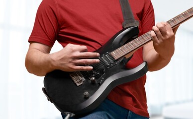 Lifestyle concept. Young musician playing guitar in the living room at home on this weekend.