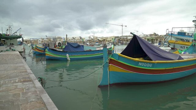 Traditional Maltese Fishing Boats Rocking on Surface of Water in Marsaxlokk Bay in Winter