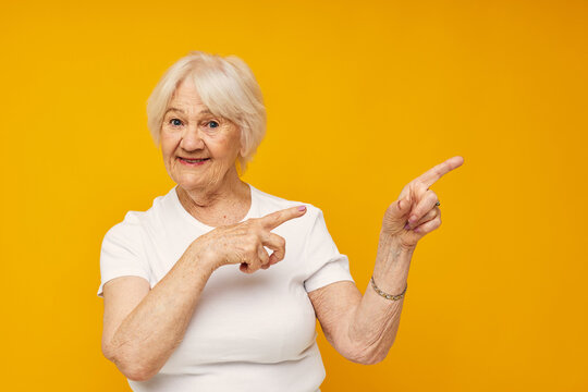 smiling elderly woman in casual t-shirt gestures with his hands cropped view