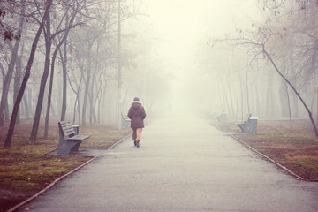 Fototapeta premium Woman traveler walks along a foggy road in the early morning. Concept of travel and adventure in Asia.