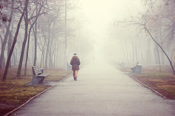 Woman traveler walks along a foggy road in the early morning. Concept of travel and adventure in Asia.
