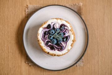 Top view of plate with Blueberry Cheesecake, pie, art. Closeup shot of berries and Rosemary placed on top. Tasty fresh baked dessert.