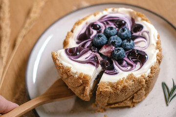 Top view of plate with Blueberry Cheesecake, pie, art. Closeup shot of berries and Rosemary placed on top. Tasty fresh baked dessert.