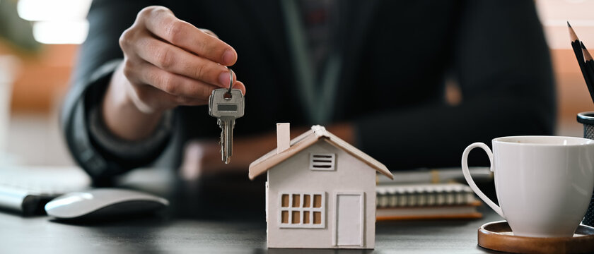 Cropped shot real estate agent  holding house key. Insurance or loan real estate concept.