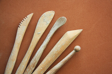 Art tools for modeling clay and pottery. Wooden artistic equipment on brown background.