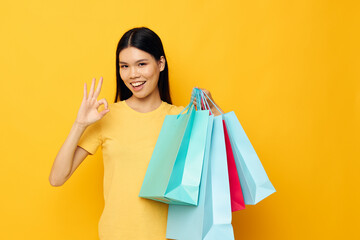 pretty brunette in a yellow T-shirt with multicolored shopping bags studio model unaltered