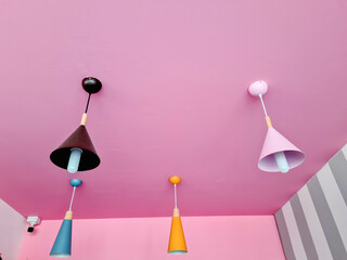 Hanging lamps and ceiling in bright pink room.