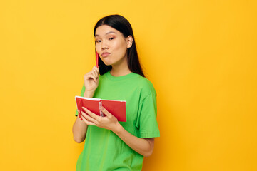 pretty brunette green T-shirts with red notebook and pen yellow background unaltered