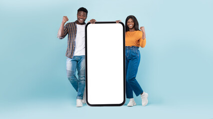 Couple showing white empty smartphone screen and making win gesture