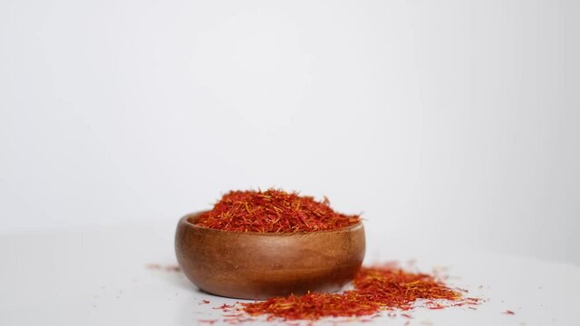 wooden bowl of saffron rotates around itself. saffron thread in the wooden plate, isolated on white background. stock footage. slow motion.