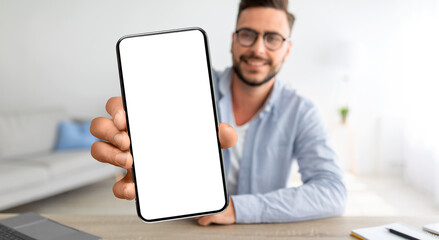 Online Ad. Smiling Young Guy Demonstrating Smartphone With Blank Screen At Home - Powered by Adobe