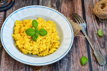  Italian  creamy risotto milanese  with parmesan cheese and fresh basil on rustic background