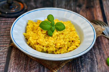  Italian  creamy risotto milanese  with parmesan cheese and fresh basil on rustic background