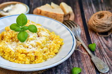  Italian  creamy risotto milanese  with parmesan cheese and fresh basil on rustic background