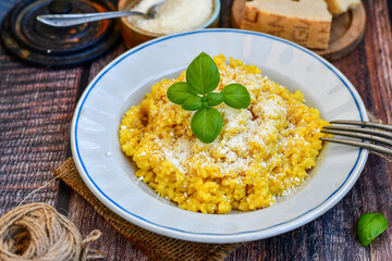  Italian  creamy risotto milanese  with parmesan cheese and fresh basil on rustic background