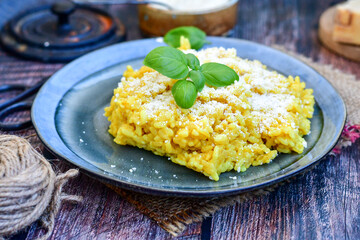  Italian  creamy risotto milanese  with parmesan cheese and fresh basil on rustic background