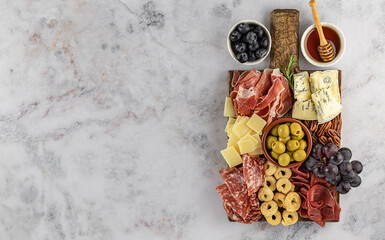 Top view of tasty charcuterie board with cheese, grape, nuts, olives, and ham on a circle kitchen plate