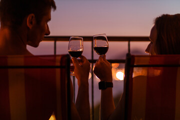 Romantic couple talking and have wine at sea view terrace at sunset. Valentine day image.